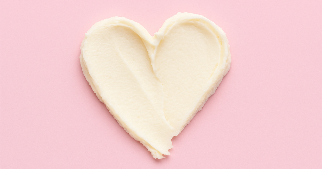 Heart-shaped swipe of cream on a soft pink background.