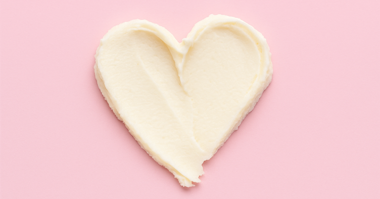 Heart-shaped swipe of cream on a soft pink background.