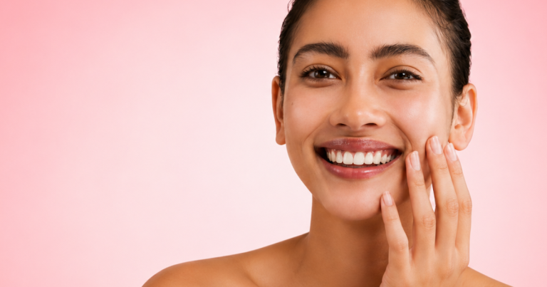 Woman with glowing skin and a light smile against a soft pink background.